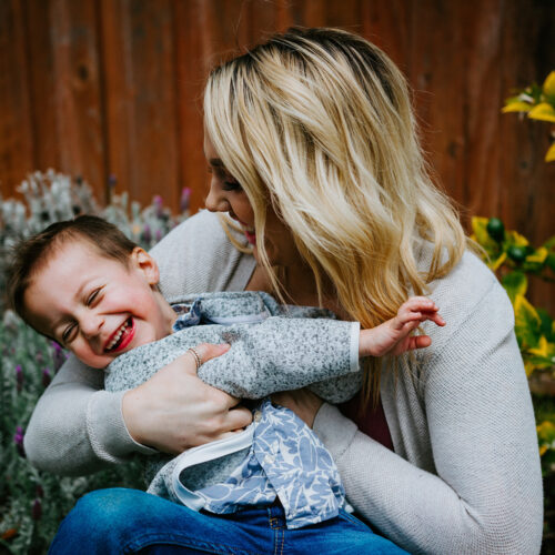 Mother and toddler boy sit laughing together