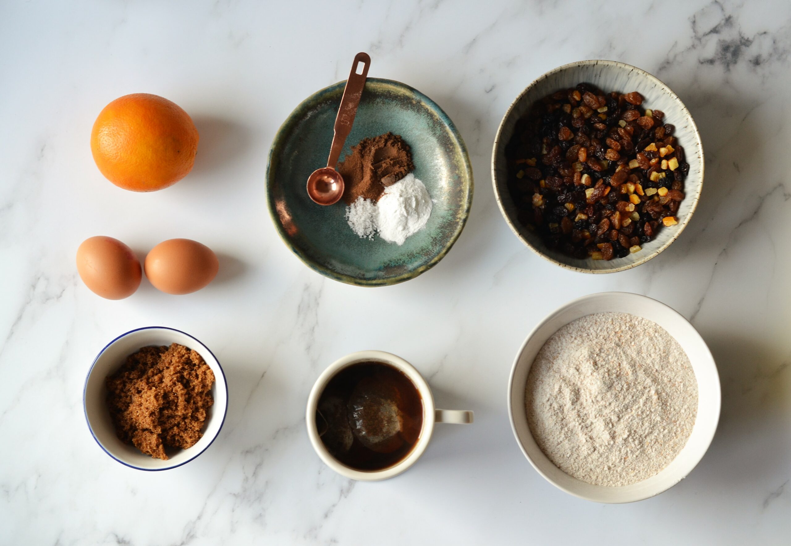 Organic ingredients in five bowls. Sugar, eggs, oranges, raisins, grains, flour.