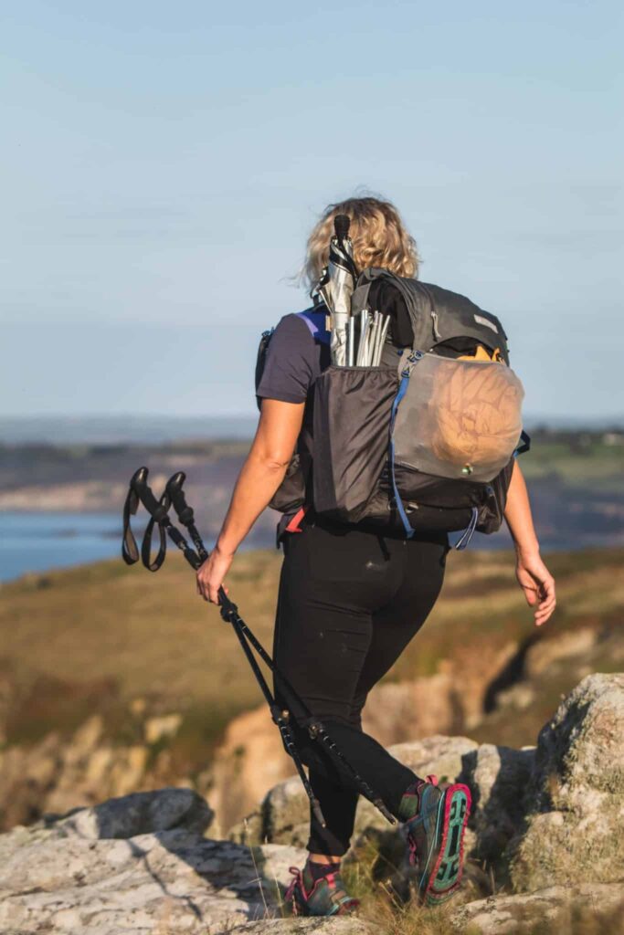 Gail carrying her poles and her backpack, walking away from the camera.