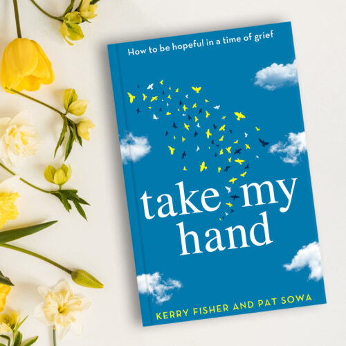 Take My Hand hardback book lies on white table next to yellow roses